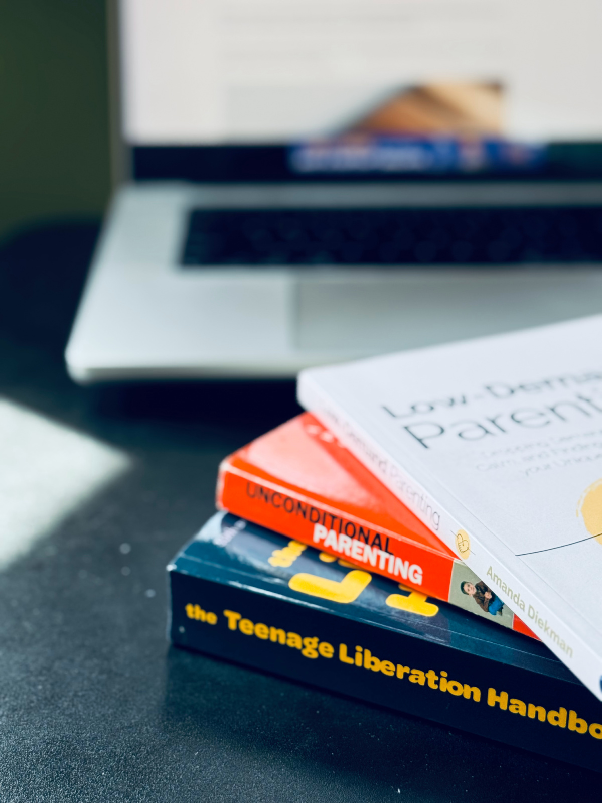 respectful parenting books on black desk with computer in background.