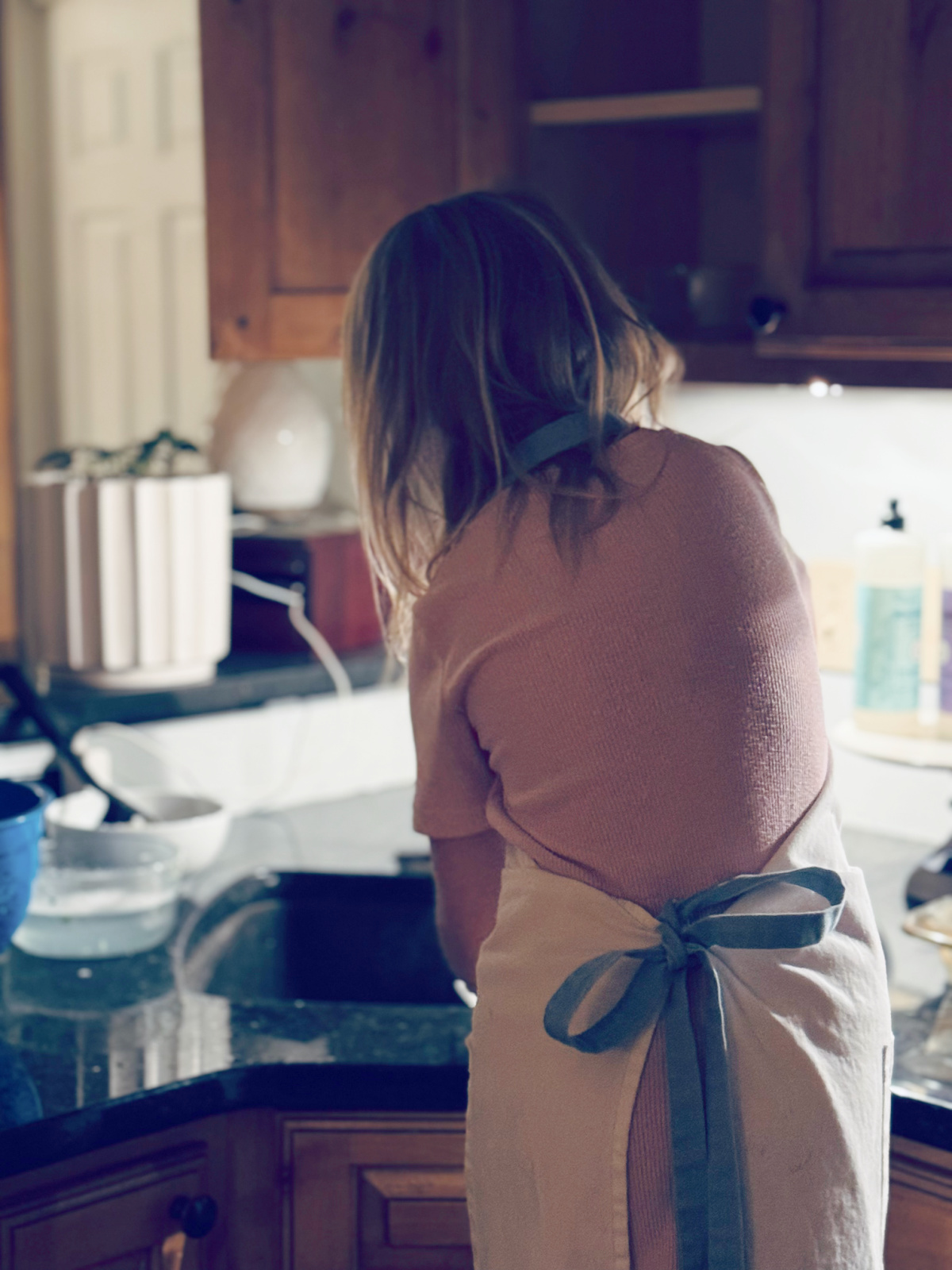 young child at kitchen sink doing dishes.