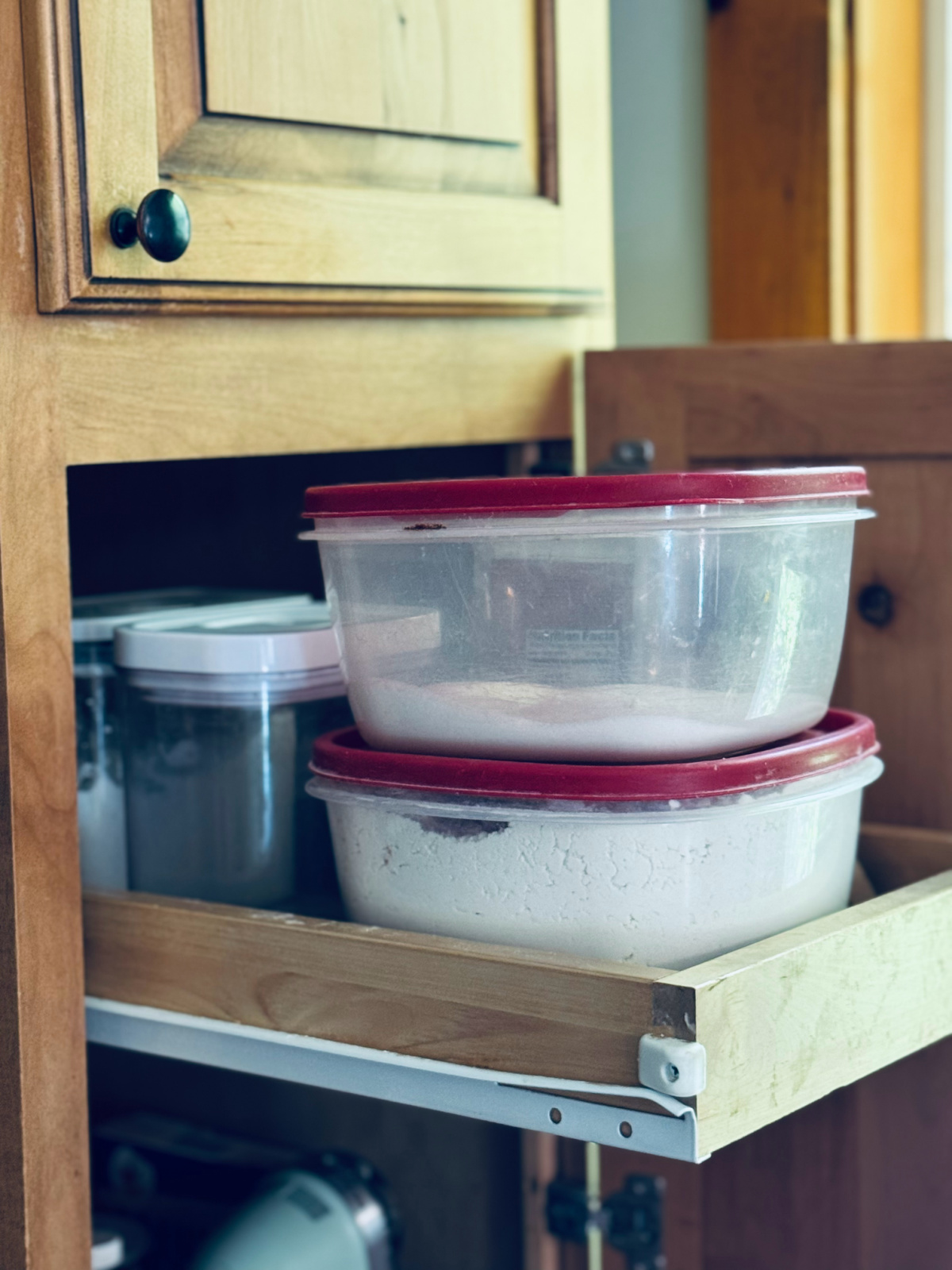 Containers of flour and sugar on baking cabinet shelf.