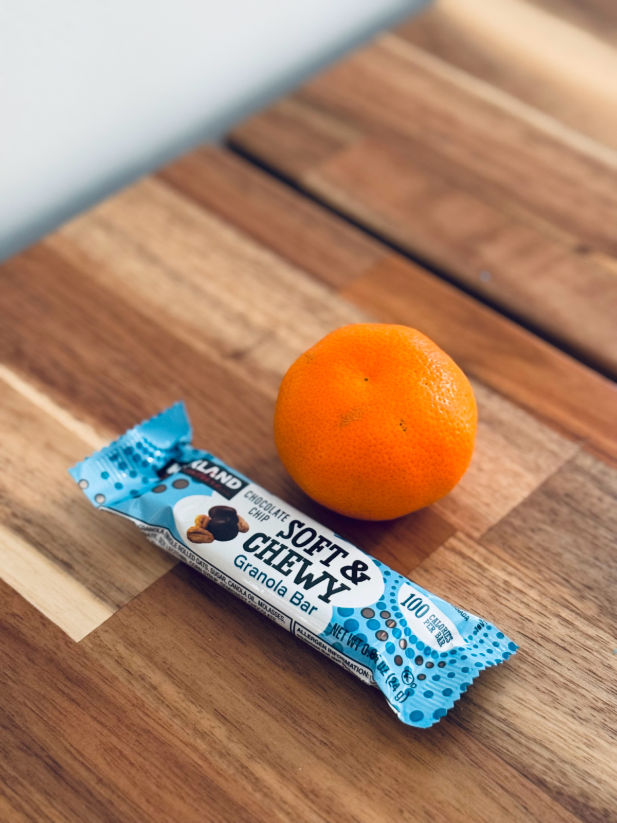 granola bar and mandarin orange on table - snack choice concept.