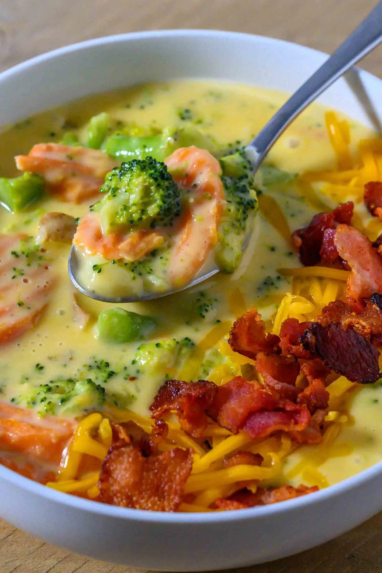 cheese vegetable soup with chopped bacon and shredded cheddar cheese.