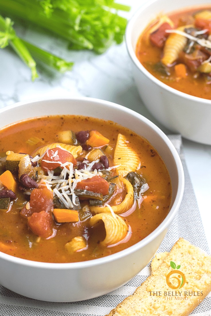 minestrone soup in white bowls with celery in background.