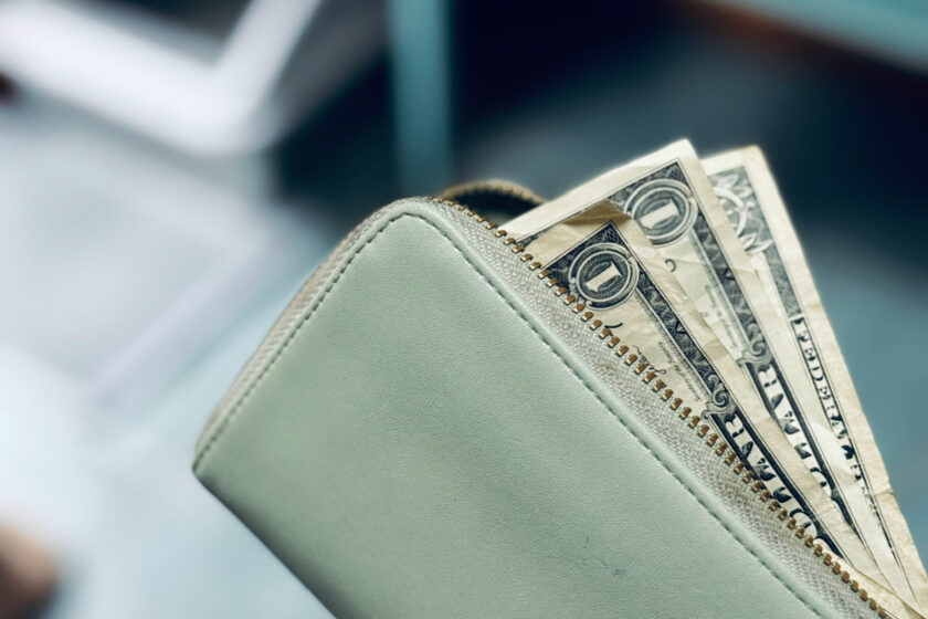 wallet with dollar bills peeking out.
