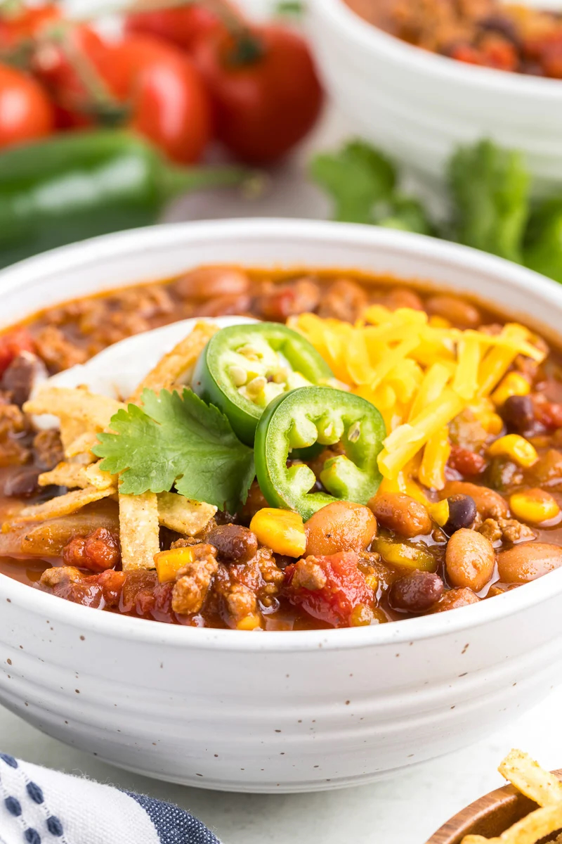 taco soup in bowl with jalapeno slices, cheddar cheese, tortilla strips and sour cream.