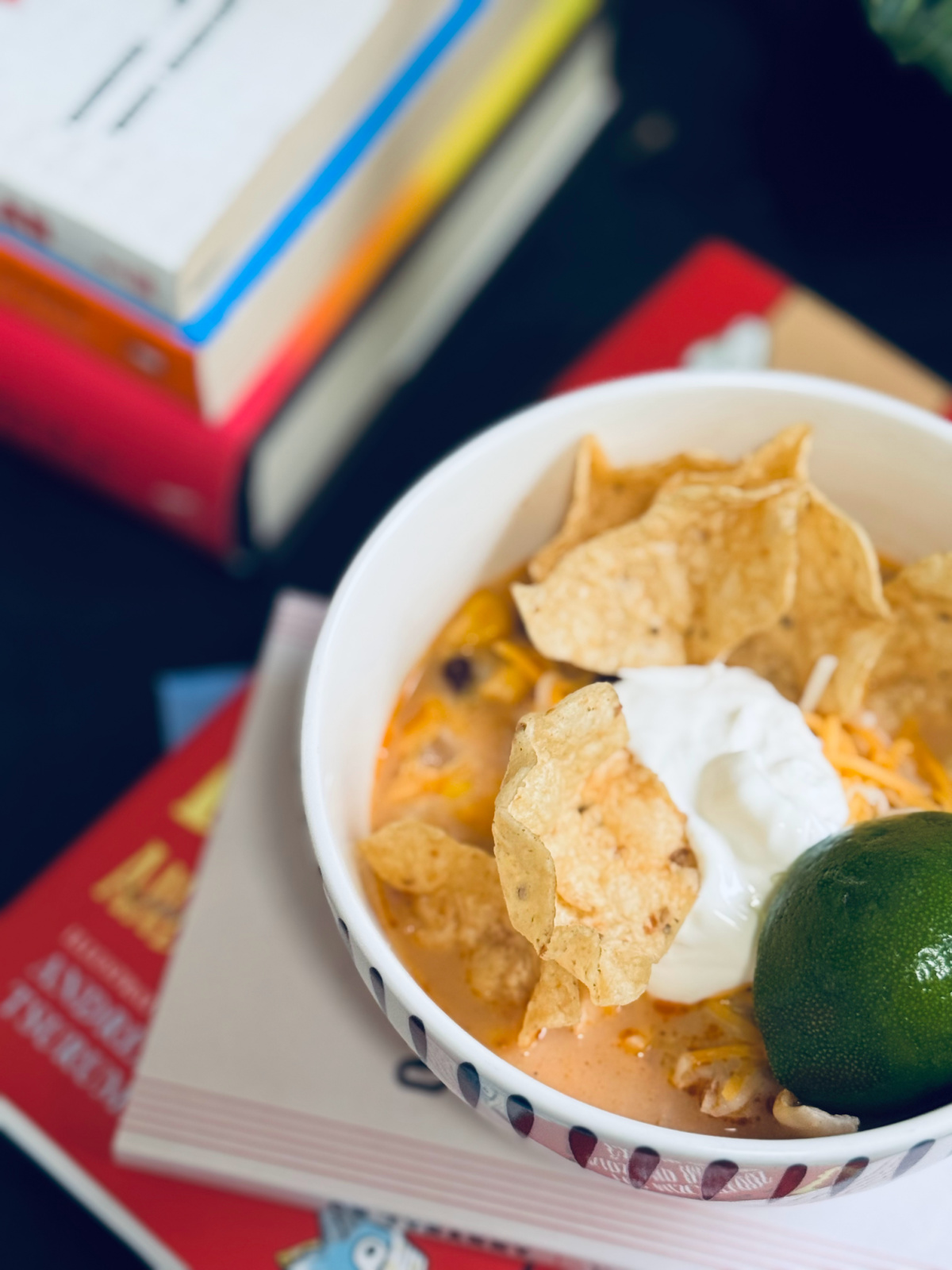 chicken tortilla soup in bowl with lime, sour cream and chips close-up.