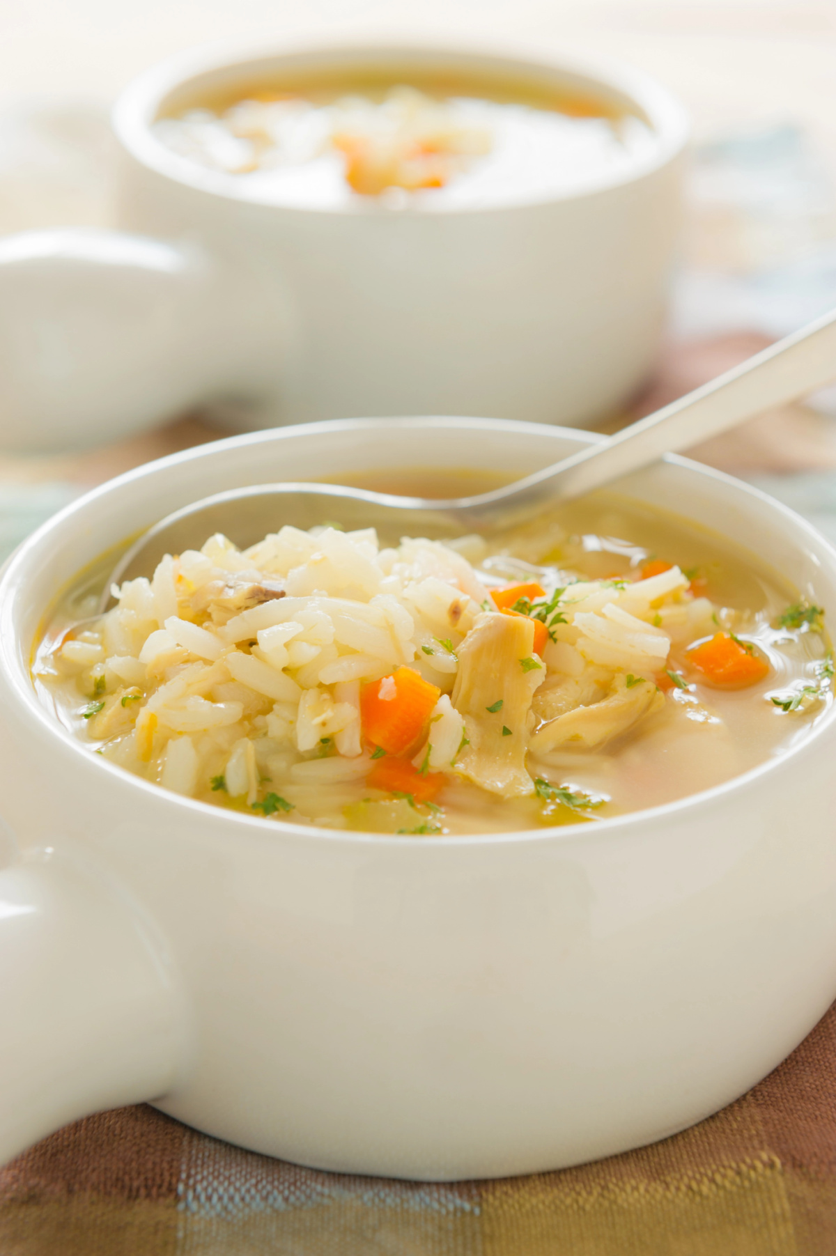 turkey and rice soup in white bowls with sturdy handles.