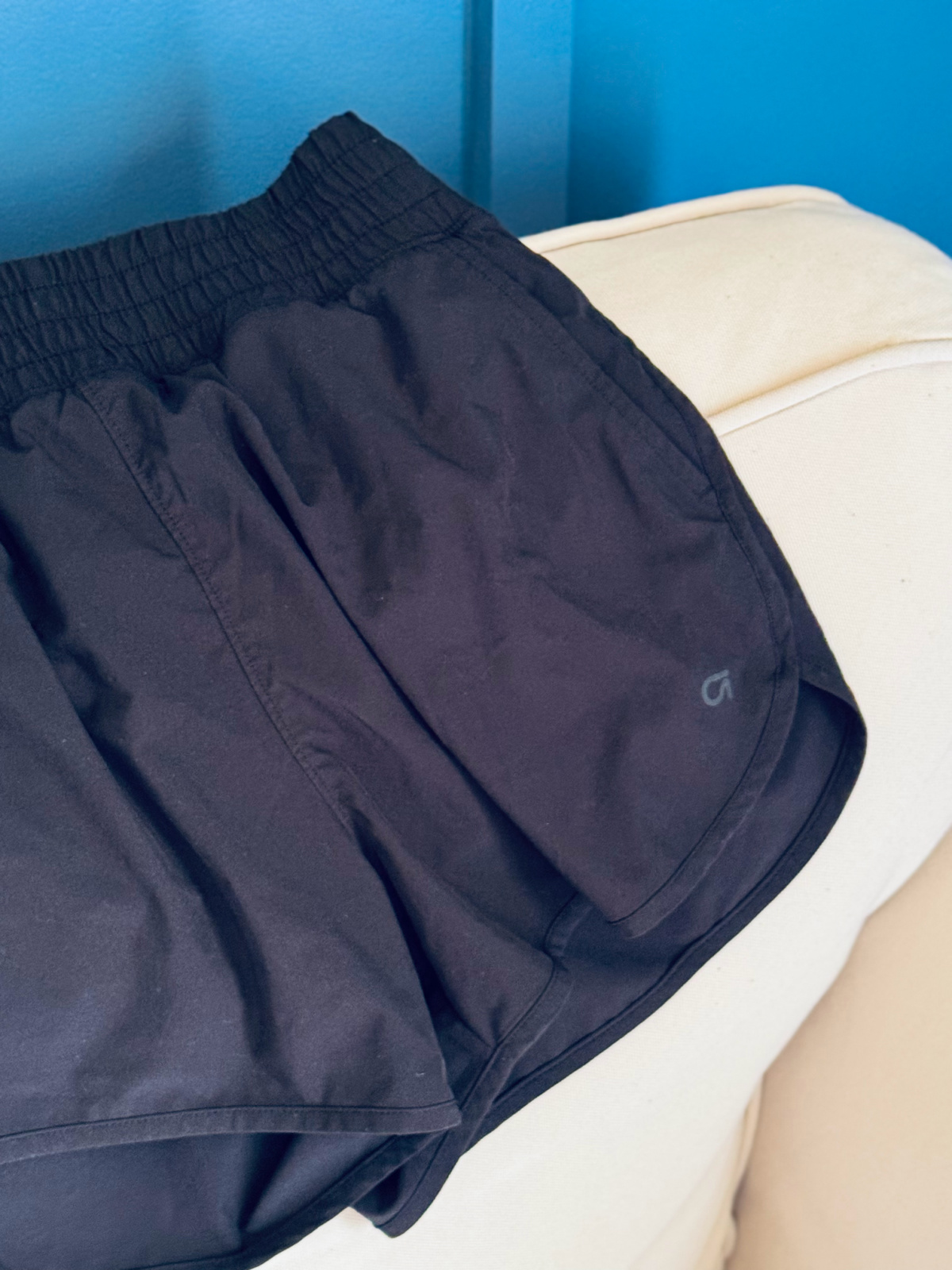 black running shorts on off-white couch.