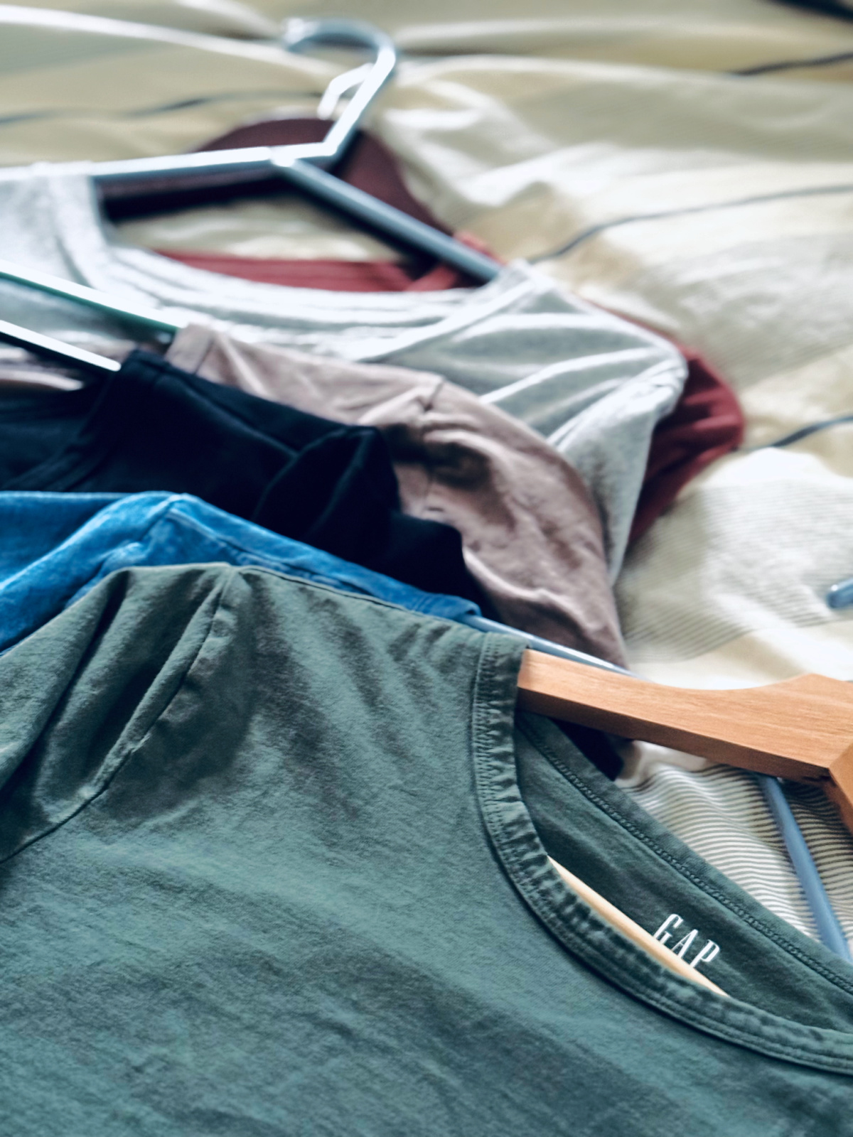 basic Gap t-shirts laid out on bed.