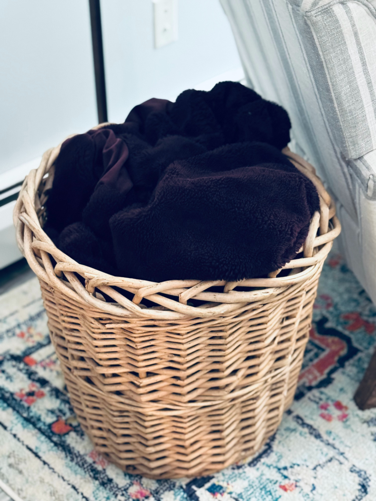 free basket from neighbor storing purple blanket next to gray and white striped chair.