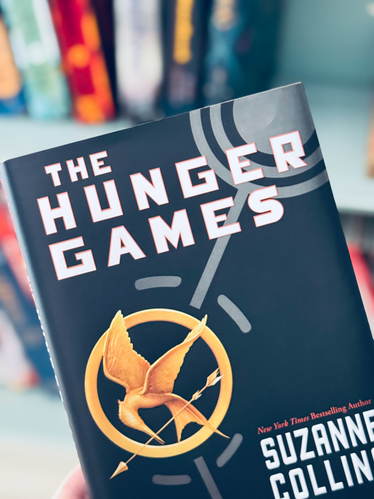 The Hunger Games book close-up with colorful books in background.
