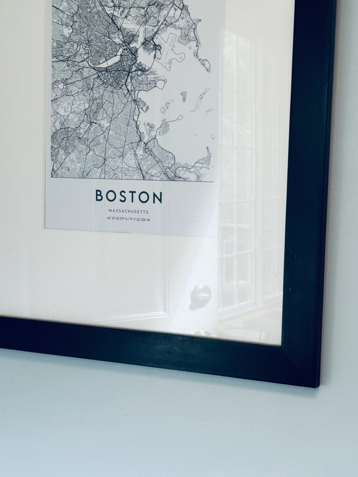 black picture frame with white mat and Boston map.