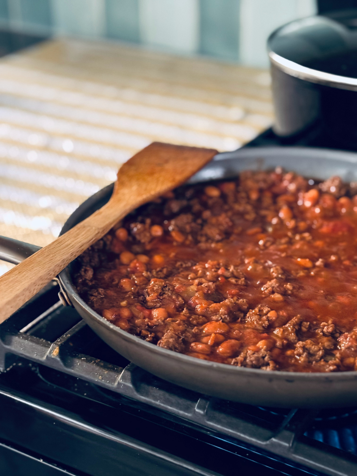 filling for stuffed peppers cooking on stovetop with yellow and white striped dish towel in background.