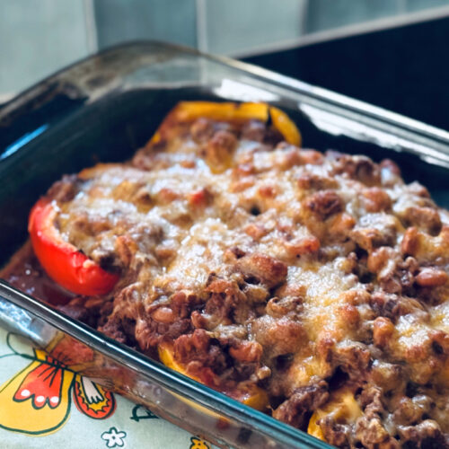 finished taco stuffed peppers in casserole dish on teal oven mitt.
