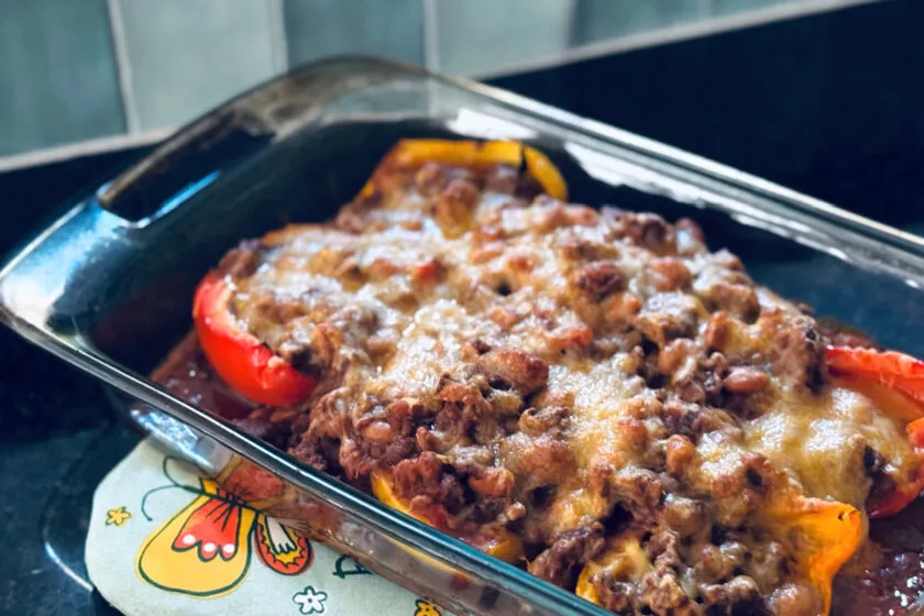 finished taco stuffed peppers in casserole dish on teal oven mitt.