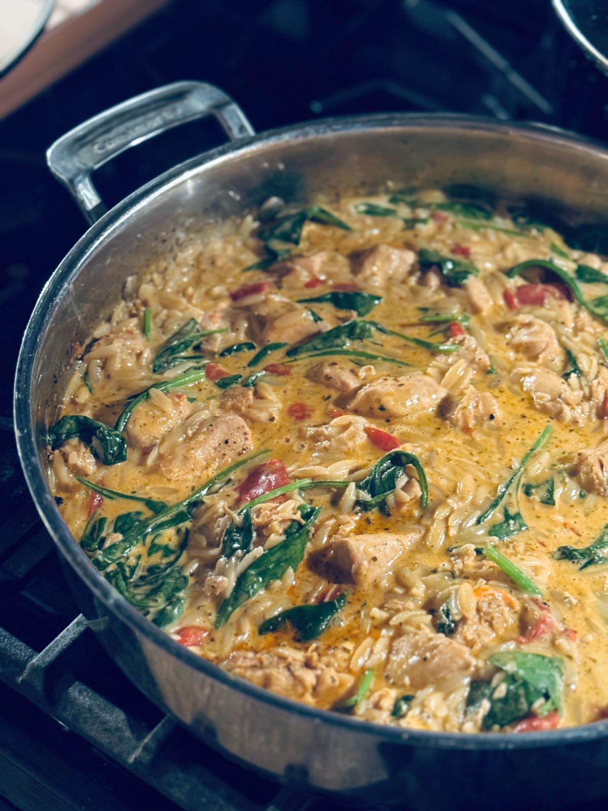 final creamy roasted red pepper chicken orzo in pan on stove
