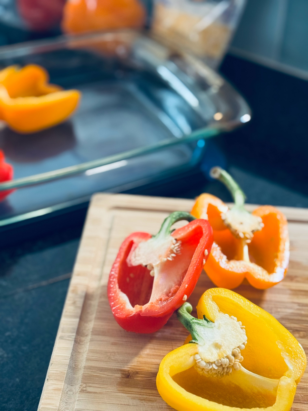 halved orange, red and yellow peppers on cutting board.