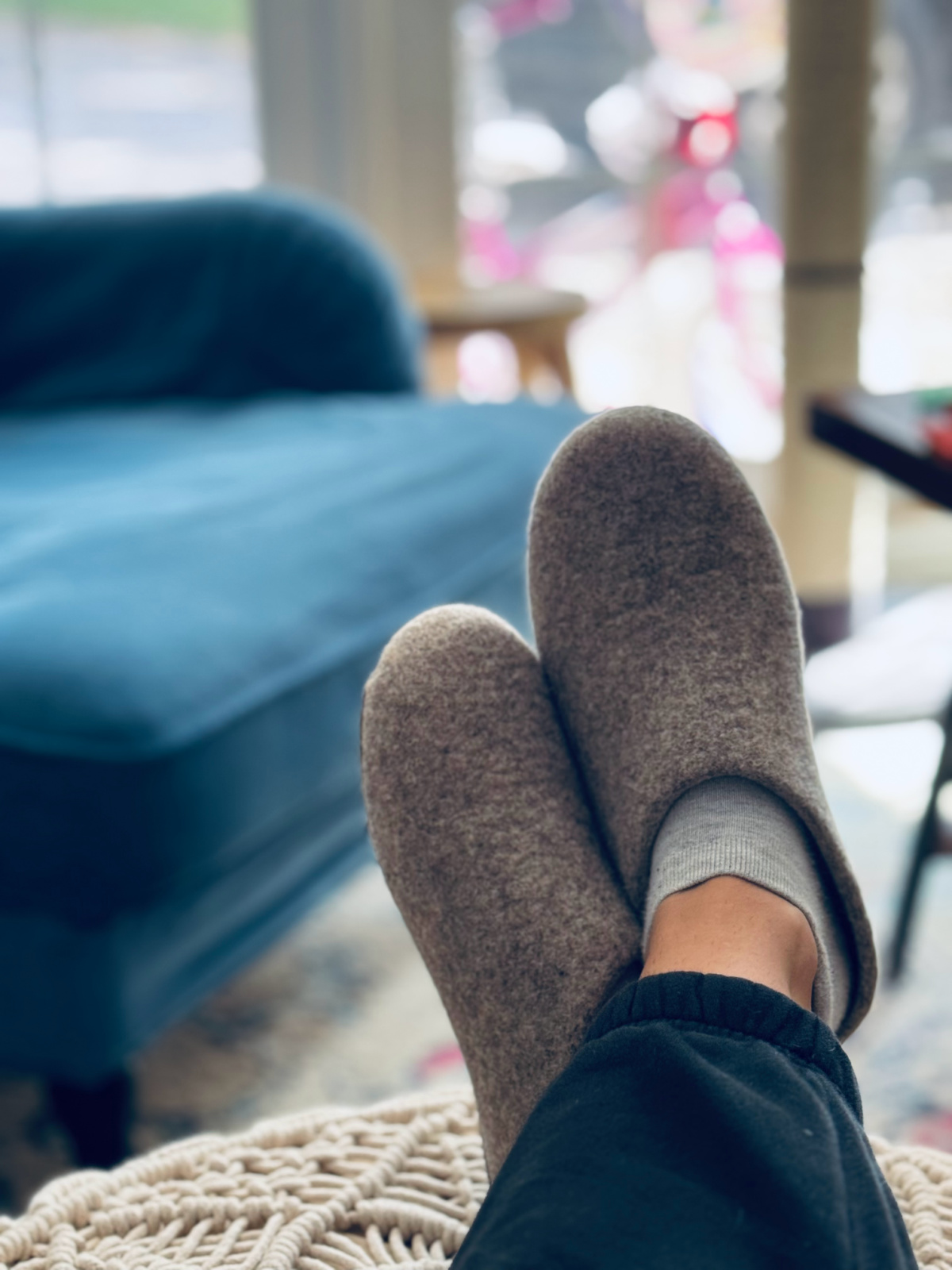 Kyrgies slippers in focus on feet resting on macrame ottoman. 