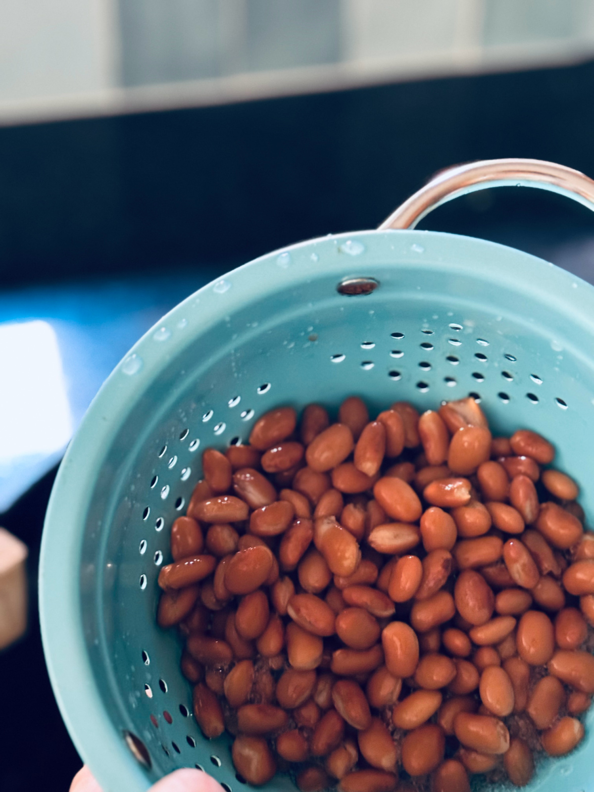 drained and rinsed pinto beans in light blue colander.