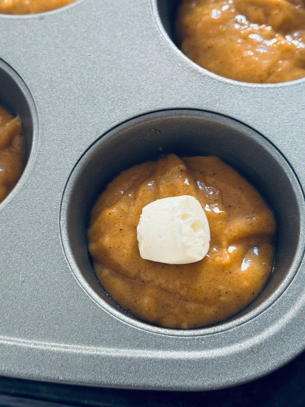 cream cheese filling on top of pumpkin muffin batter in process of making.