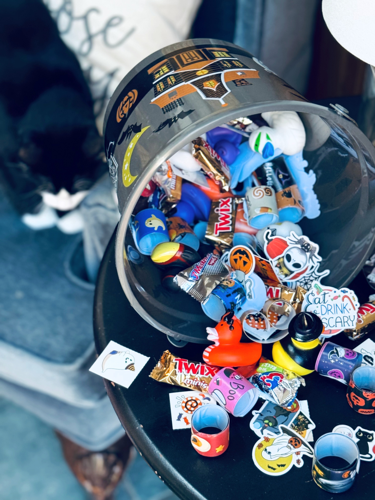 halloween candy alternatives mixed with candy in halloween bucket with black cat in background.