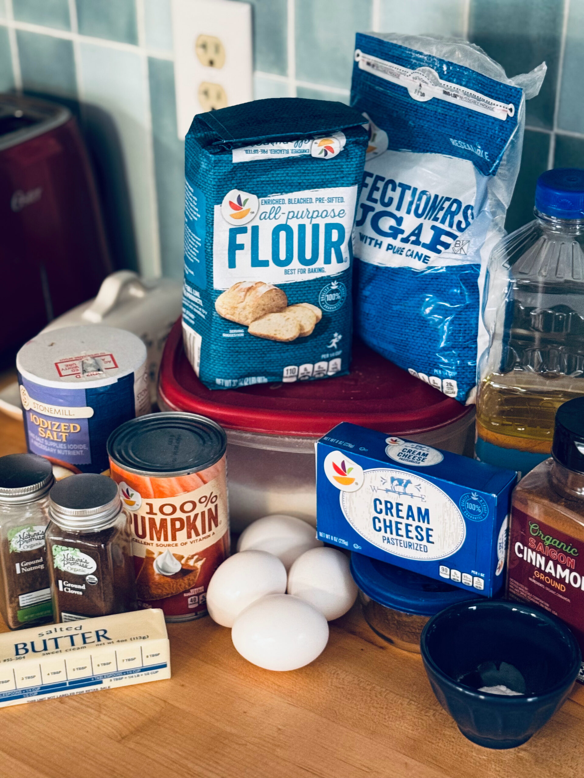 ingredients for pumpkin cream cheese muffins on counter with light blue tile backsplash in background.