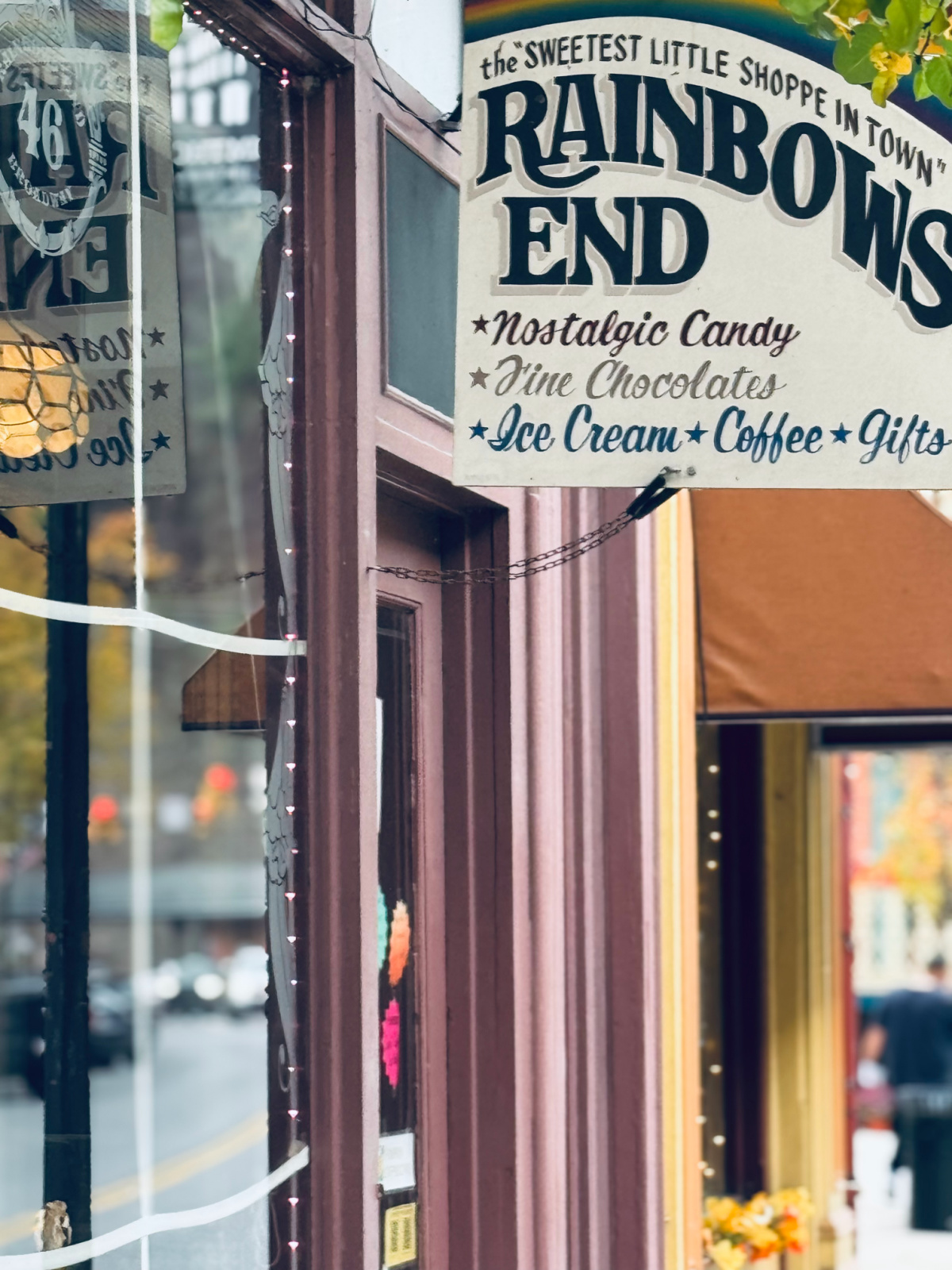 "Rainbow's End" candy shop sign in focus, shop local for Christmas theme.