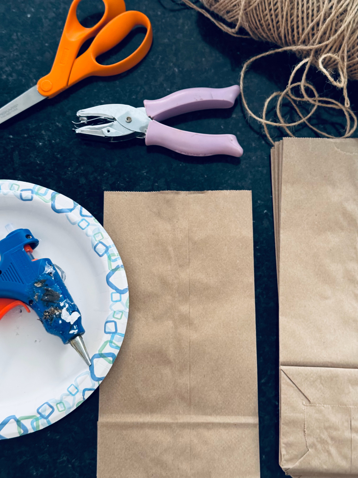 supplies for paper bag stars laid out on black countertop