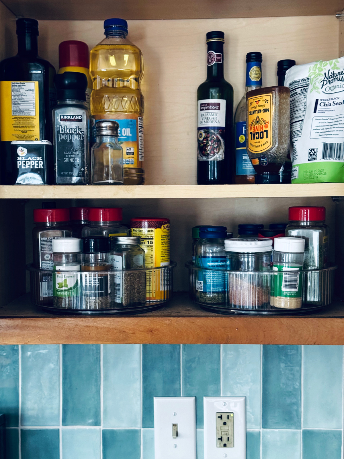 spices in lazy susan organizers with oils on the shelf above.