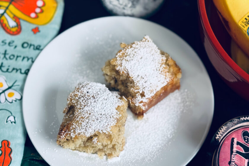 banana bread slices on white plate with powdered sugar on top.