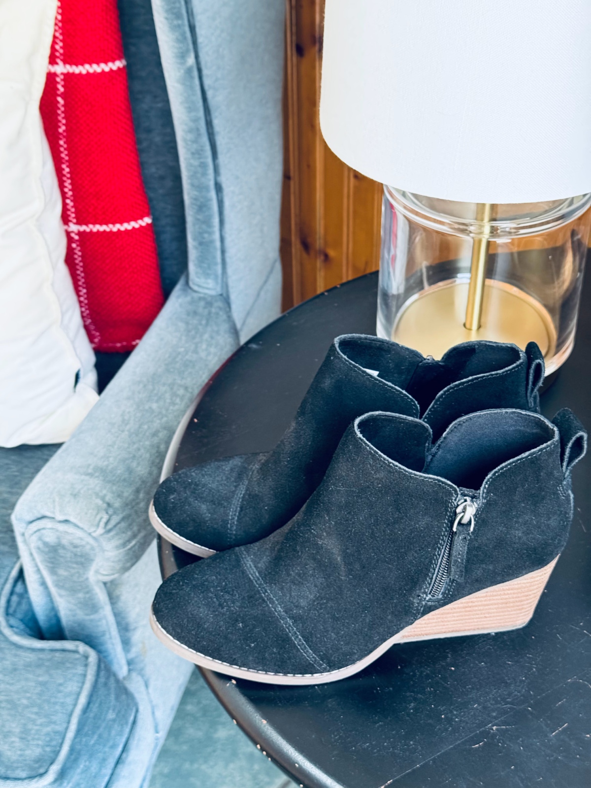 black TOMS booties on black table near gold lamp and chair.