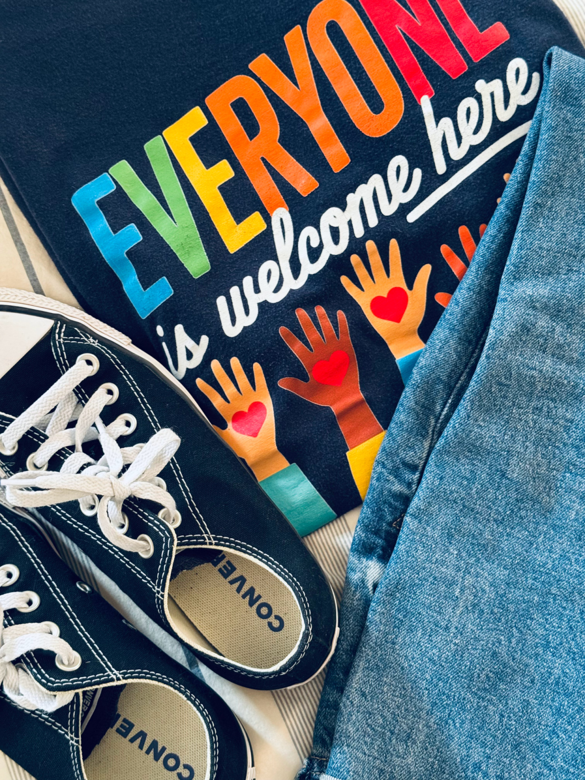 jeans and converse and a t-shirt that says, "everyone is welcome here."