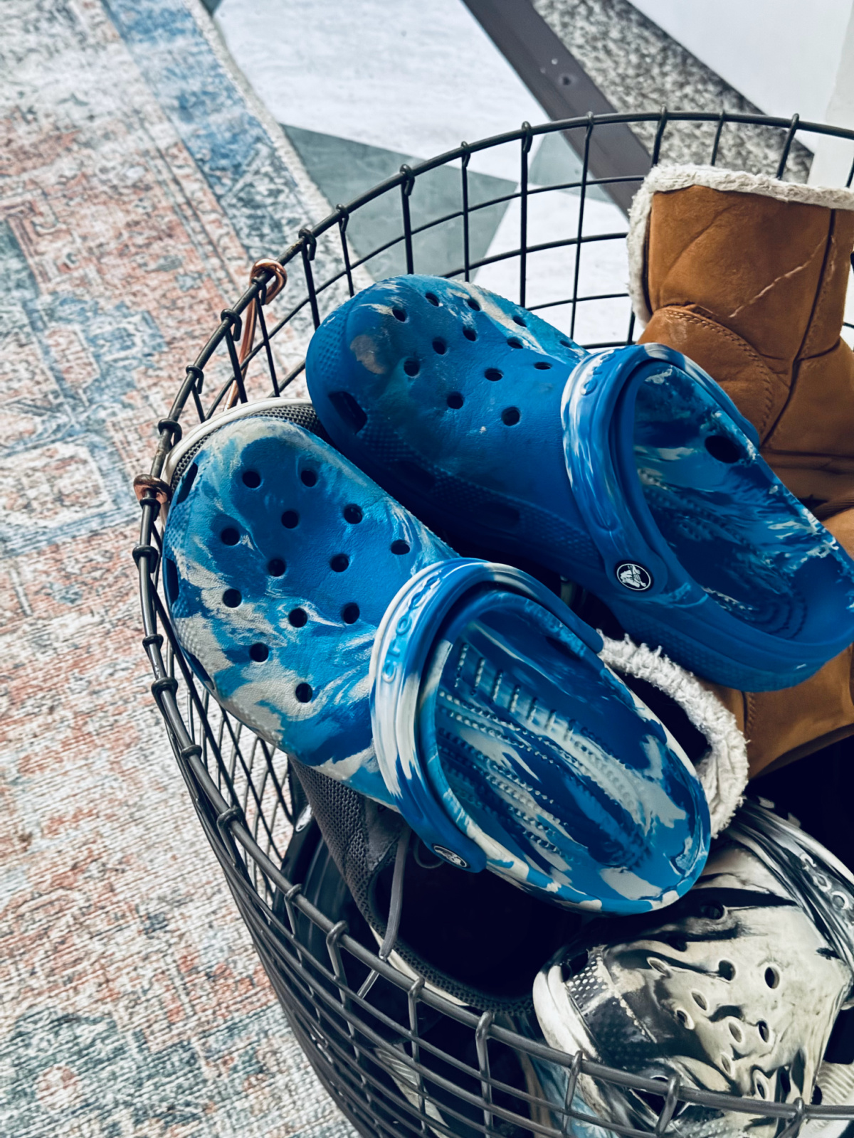 blue and white marbled Crocs in shoe basket with other shoes.