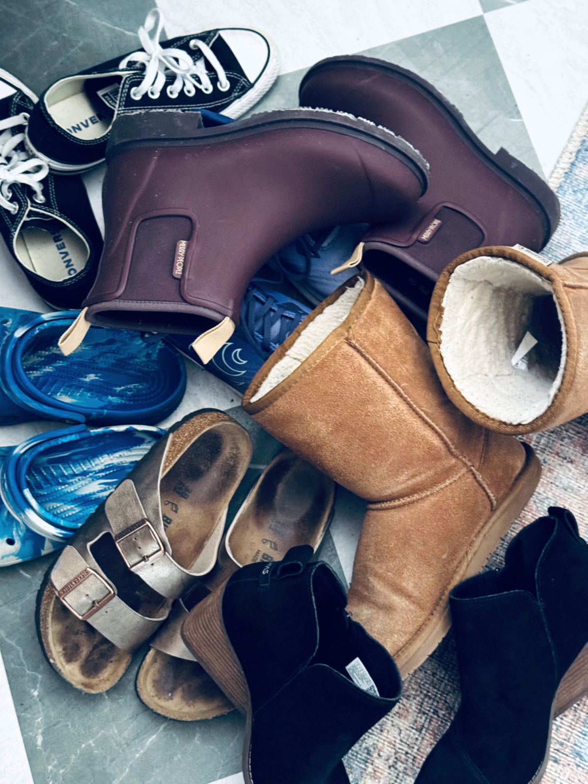 minimalist shoe collection pile on green and white checkered flooring.