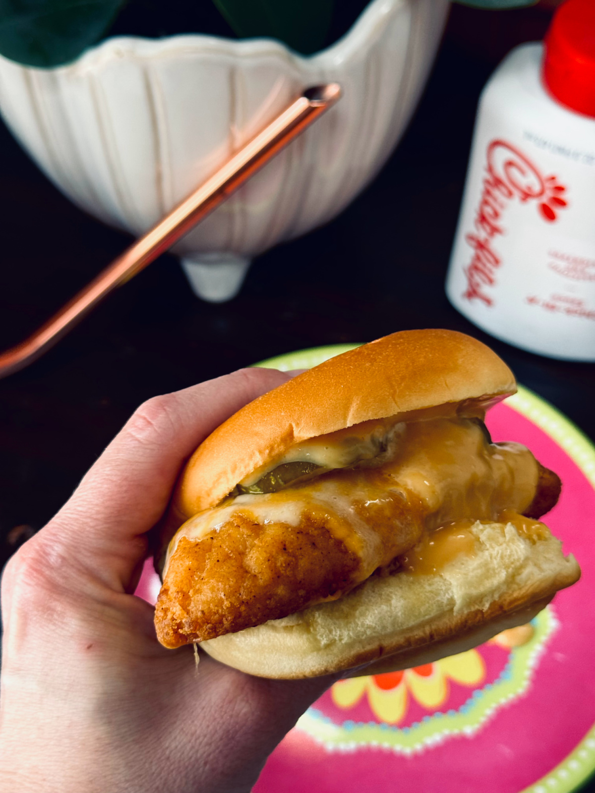 copycat chick fil a chicken sandwich with melted colby jack cheese, side view with hand holding sandwich.
