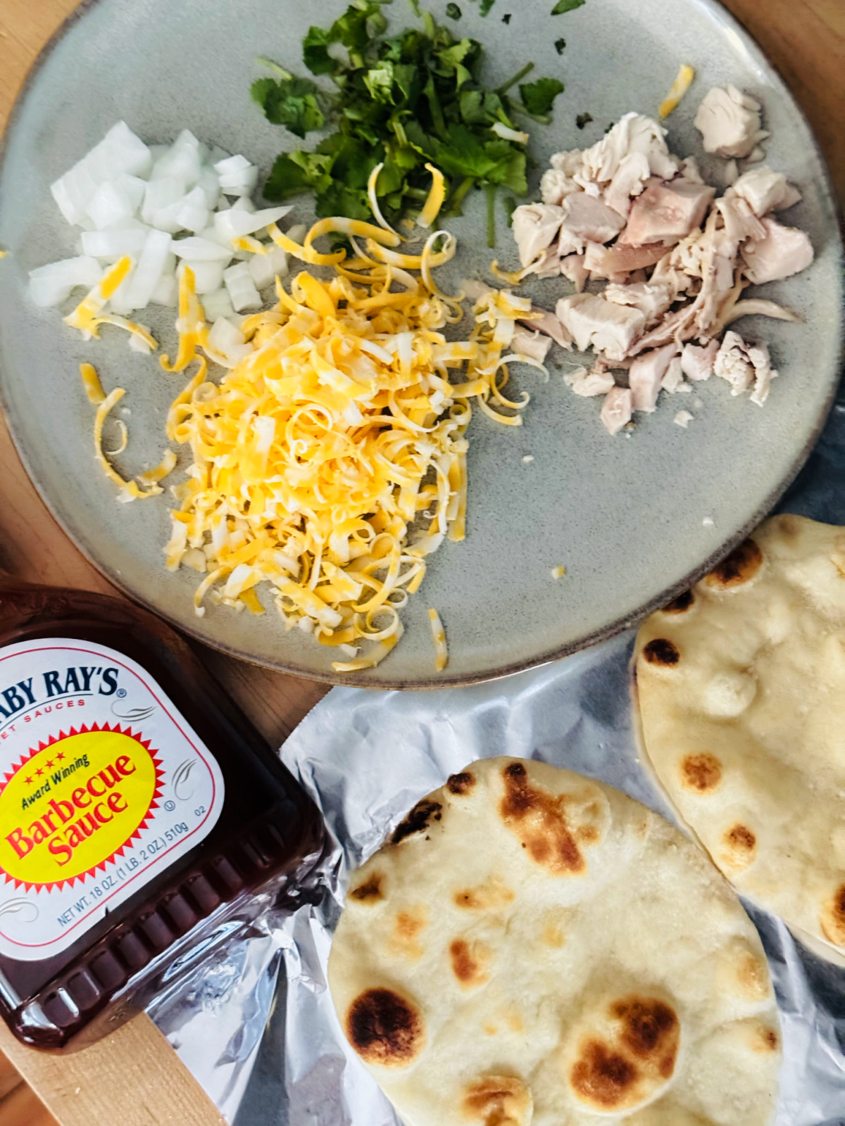 ingredients for mini bbq chicken naan pizzas in flat lay style.