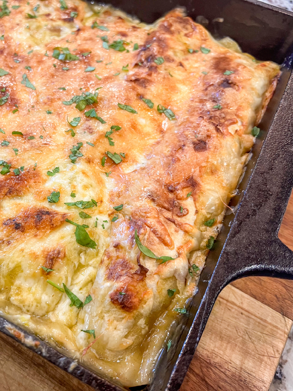 green chili chicken enchiladas in casserole dish.