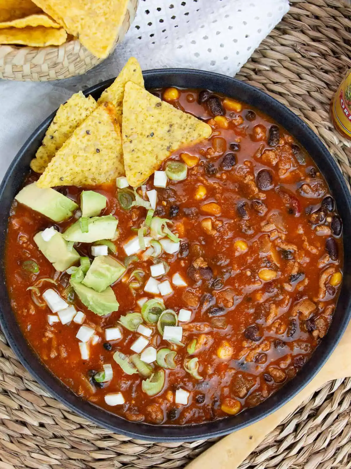 ground beef taco soup in blue bowl with tortilla chips in Mexican themed dinner for families.