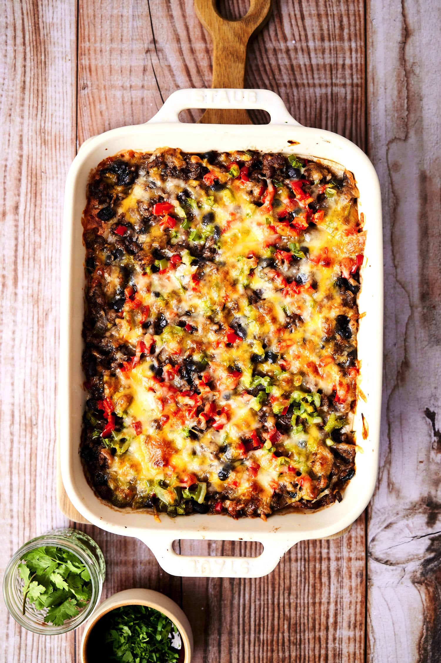 creamy burrito casserole in white casserole dish on kitchen table.