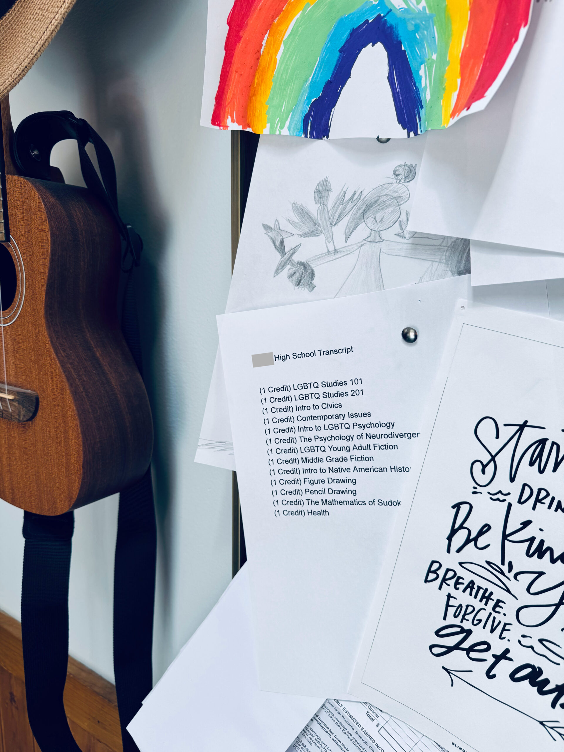 unschooled child's high school transcript on bulletin board with other papers and ukulele.