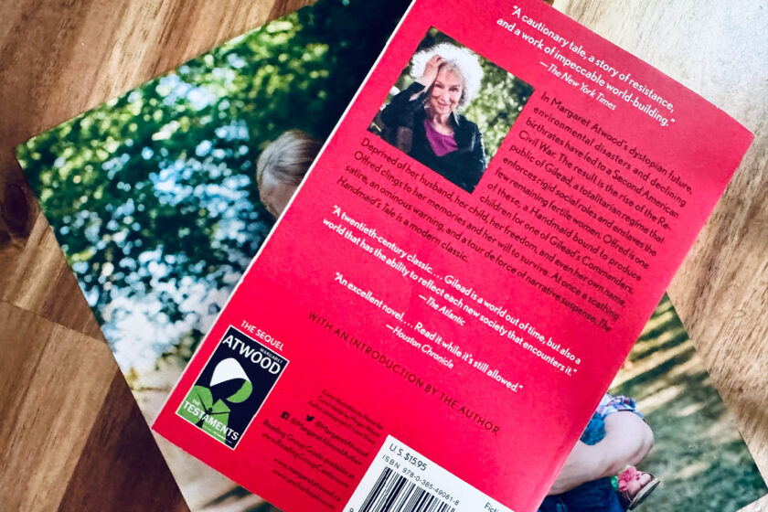 back of book The Handmaid's Tale on top of family picture.