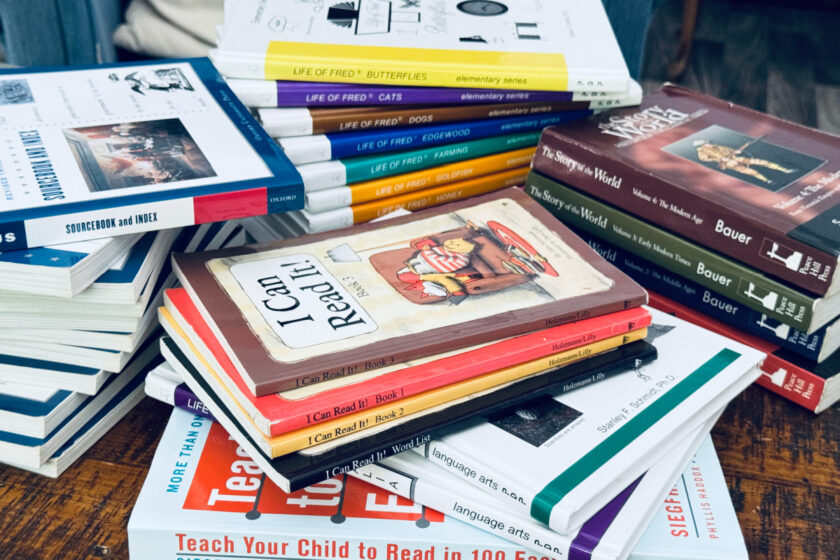 homeschool clutter in piles on coffee table.