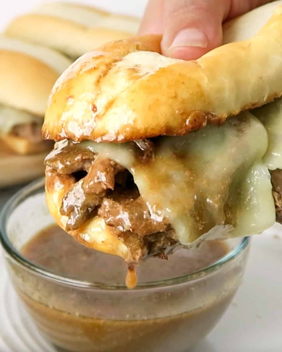french dip sandwich close-up, hand holding sandwich over dip.