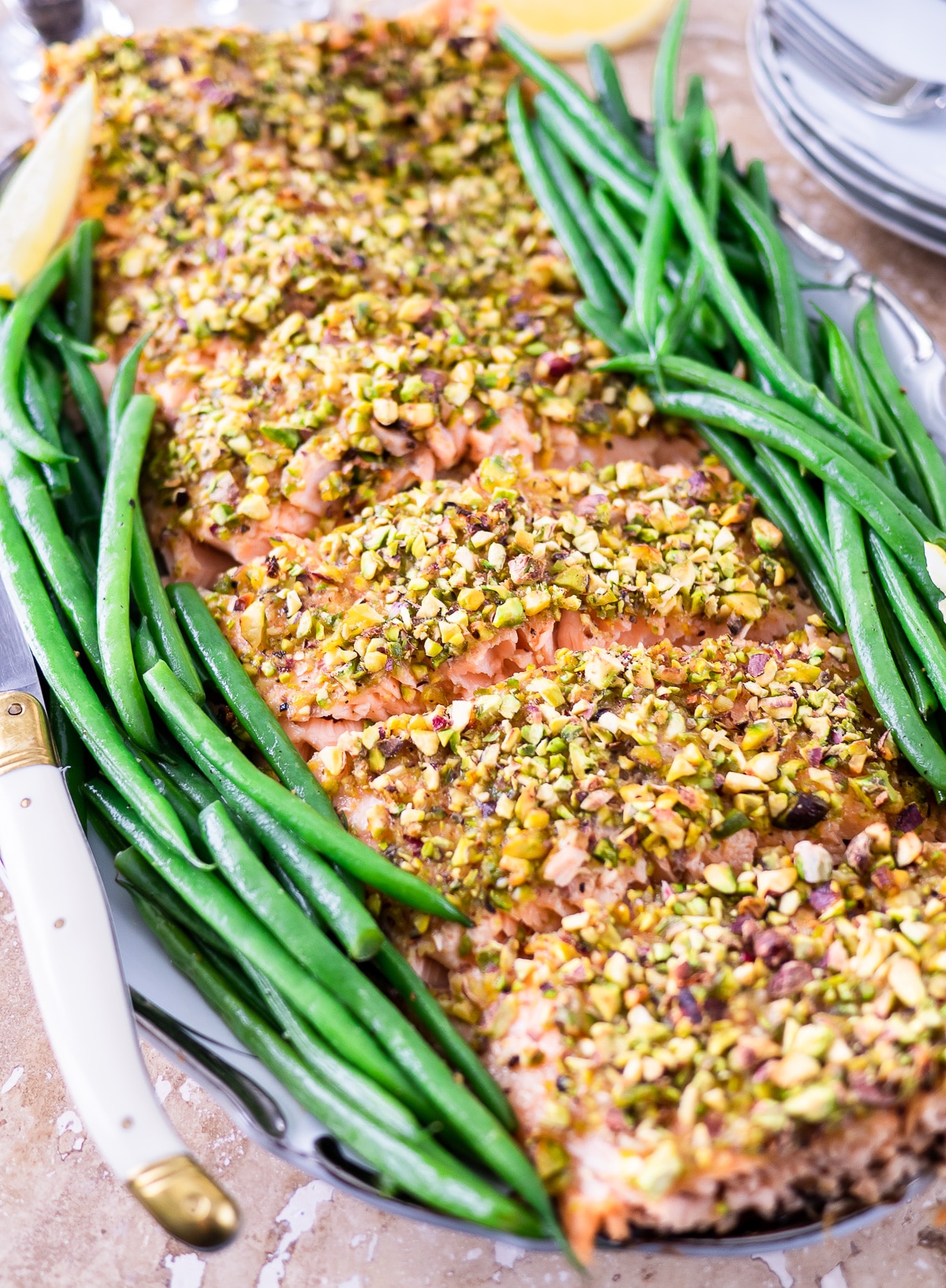 finished pistachio crusted salmon on platter with green beans.