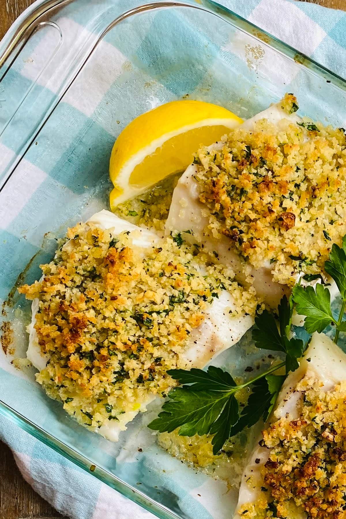 baked panko cod in glass dish with lemon and parsley.