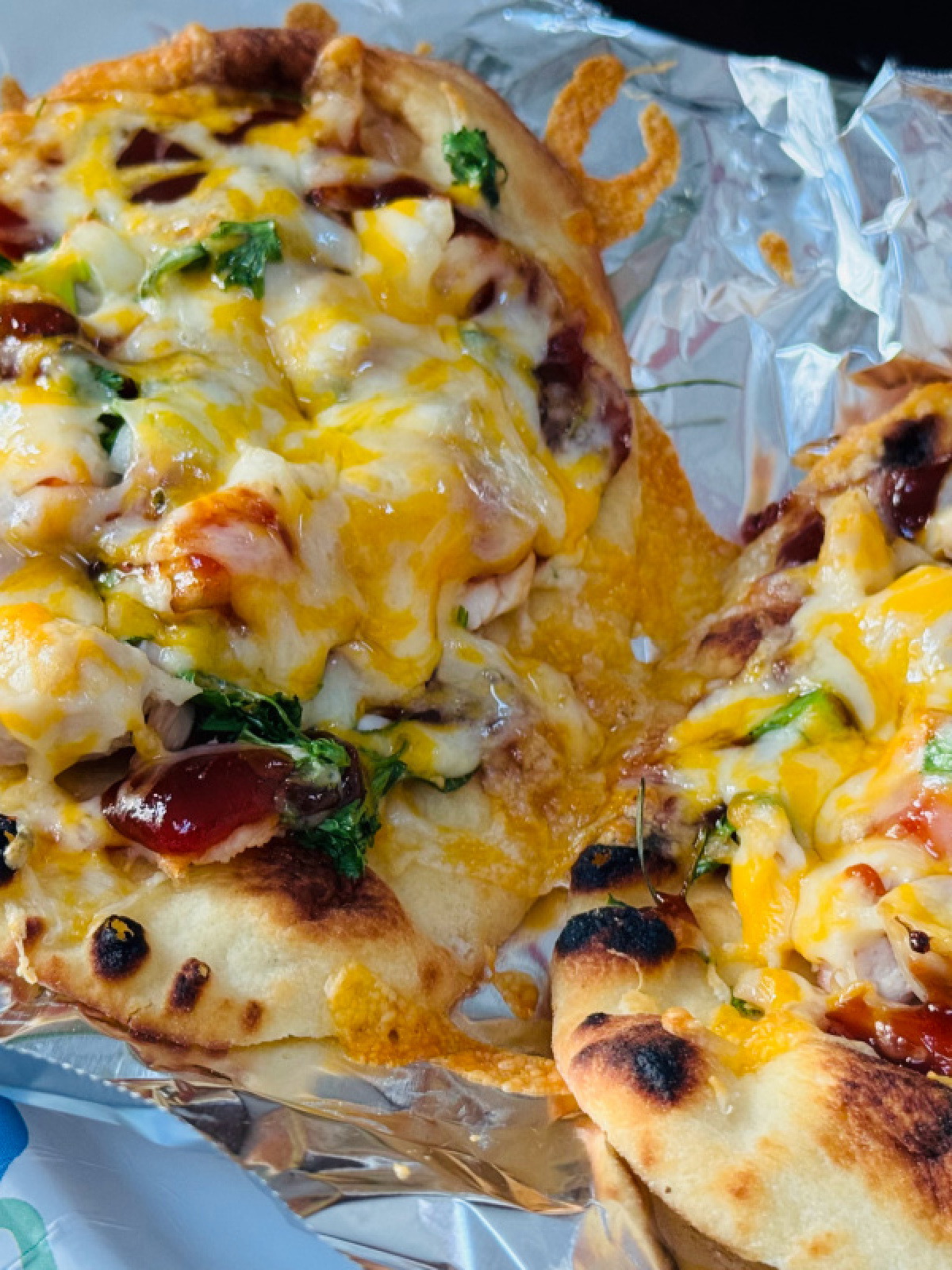 mini bbq chicken naan pizzas on aluminum foil.