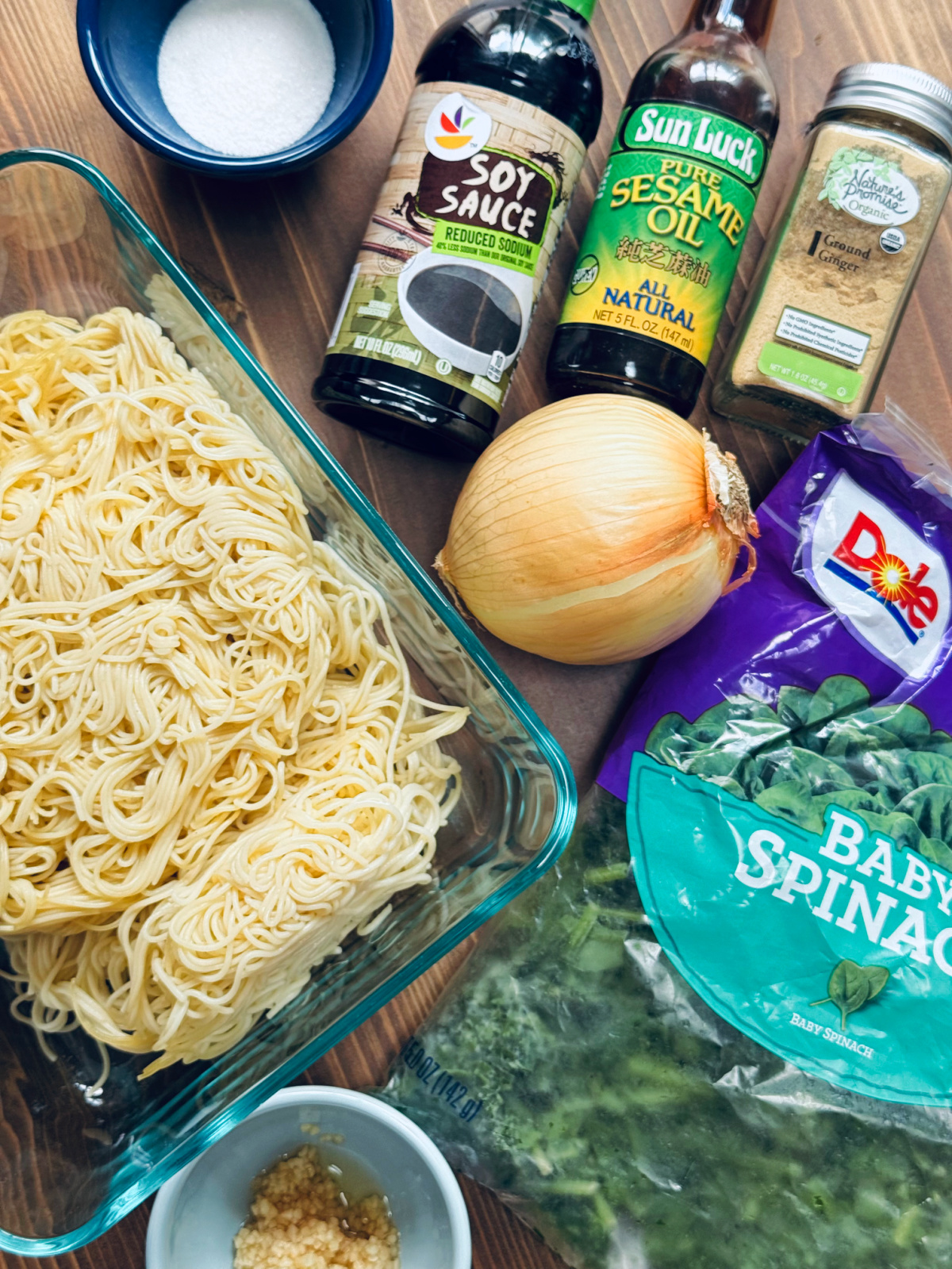 leftover pasta, onions, baby spinach, soy sauce, ginger, sesame oil, white sugar on board, ingredients for easy lo mein.